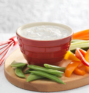 Spicy Thai Lime Dip in a red serving dish on top of a wooden tray with assorted raw vegetables.