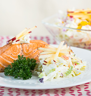 Apple Coleslaw made with Astro yogurt served on a white plate with Salmon and parsely