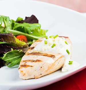 Grilled Chicken Breasts with Blue Cheese Sauce made with Astro yogurt served alongside a green salad