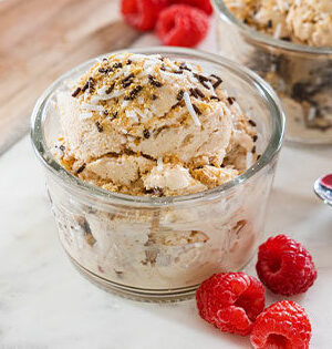 Original Nanaimo Bar Frozen Yogurt in a glass serving dish sitting on top of a marble counter top with raspberries.